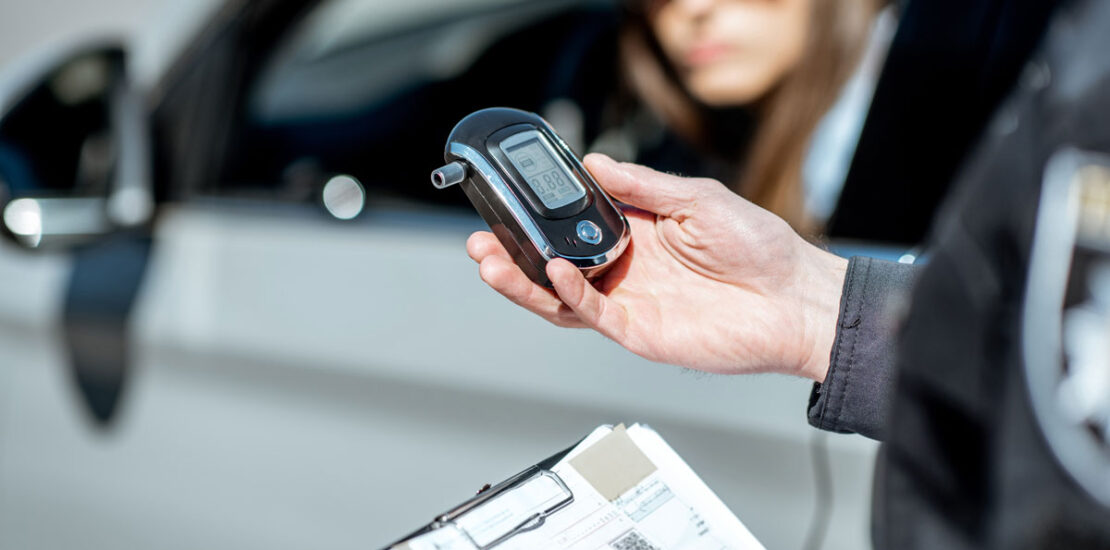 A police officer preparing a breathalyzer machine for a woman driver to test for impaired driving.