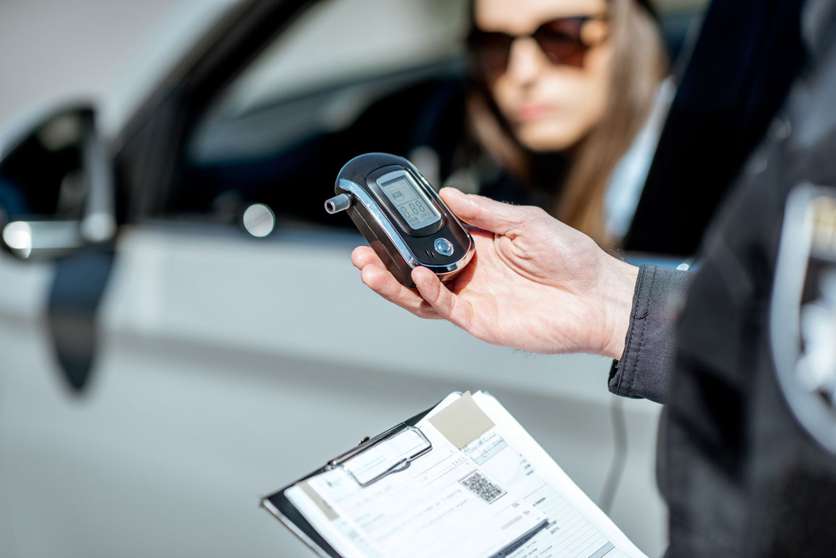 A police officer preparing a breathalyzer machine for a woman driver to test for impaired driving.