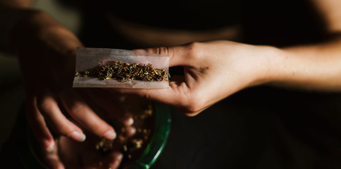 Young woman rolling a joint, symbolizing the risk of impaired driving.