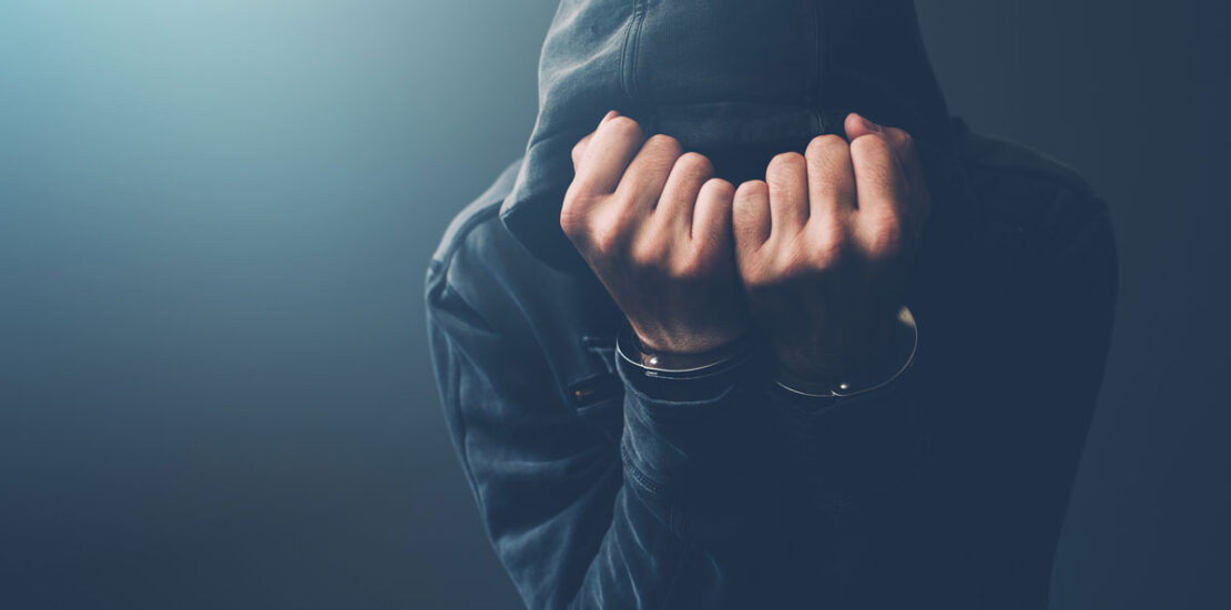 A man in handcuffs with his hood on, suggesting the need for a criminal defence lawyer in an incest case.