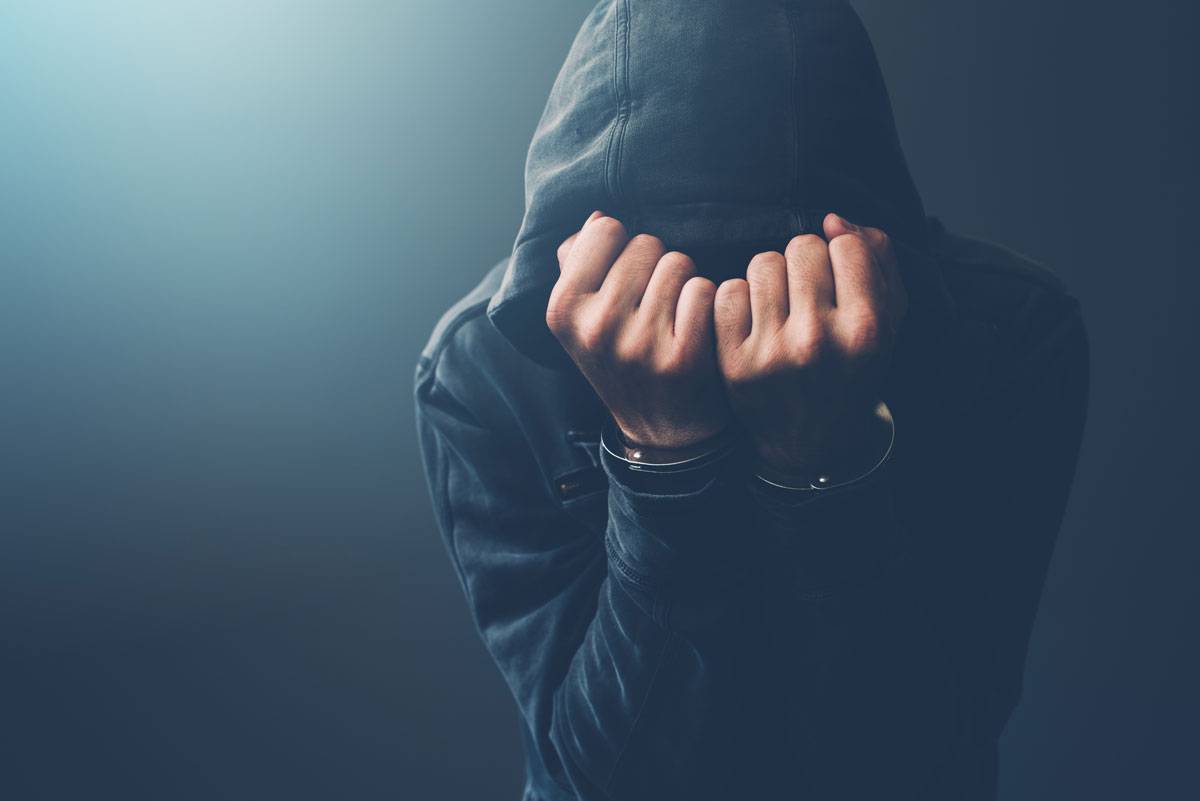 A man in handcuffs with his hood on, suggesting the need for a criminal defence lawyer in an incest case.