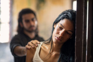 Victim of domestic abuse with her partner in the background, suggesting the need for a domestic violence lawyer.