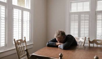 A distressed man sitting at a table, in need of a criminal lawyer for a sexual assault charge.