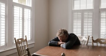 A distressed man sitting at a table, in need of a criminal lawyer for a sexual assault charge.